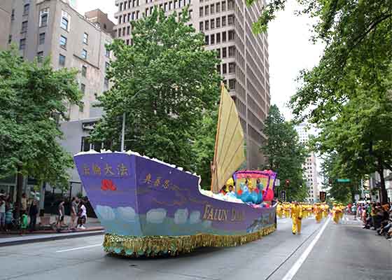 Image for article Seattle : Les gens applaudissent le groupe du Falun Dafa lors du défilé aux flambeaux de Seafair